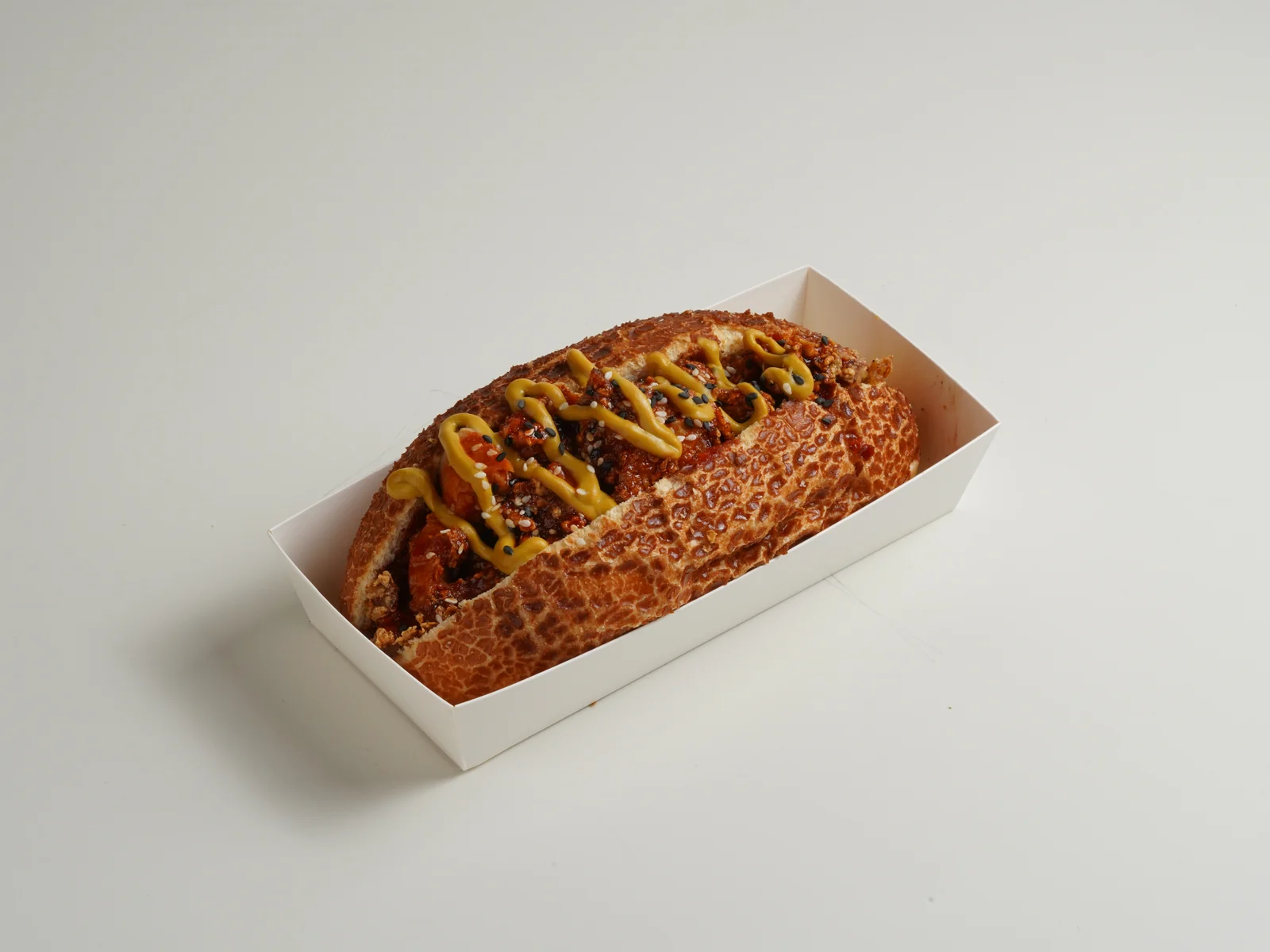 Before food photo editing: a gochujang hotdog straight out of camera, with a grey cast, flat colour and sauce marks on the tray